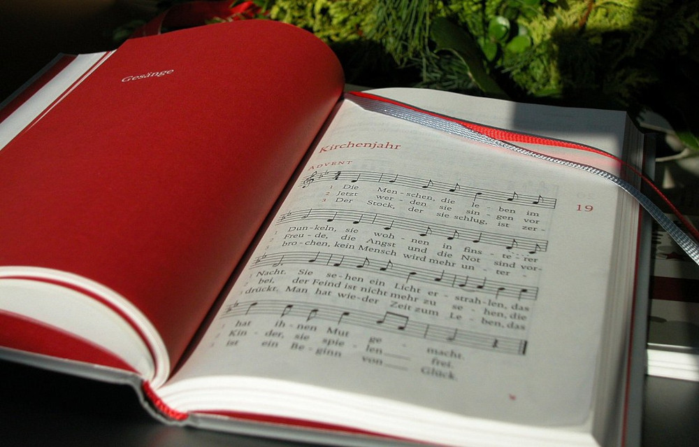 Das Gesangsbuch liegt aufgeschlagen auf dem Tisch. Auf der linken Seite steht 'Gesänge' und rechts ist das Lied 'Kirchenjahr' aufgeschlagen