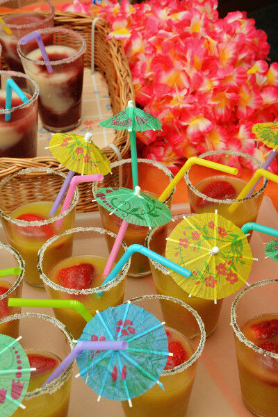 Mottoparty: Leckere Cocktails mit Schirmchen und Blumenketten im Hintergrund